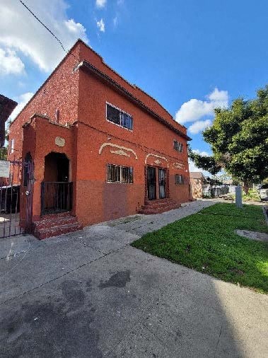 a red brick building with a sidewalk and grass