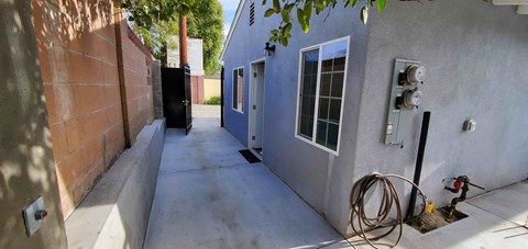 the side of a house with a long sidewalk and a door