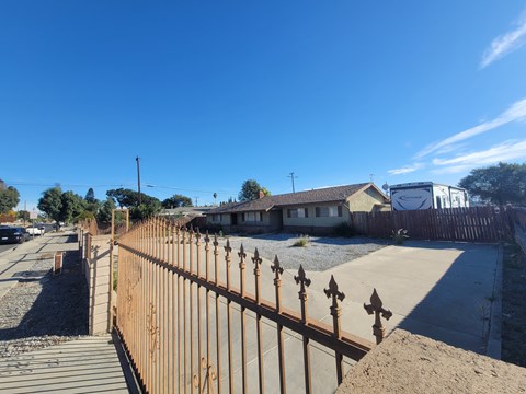 A brown fence with pointed tops stands in front of a house.
