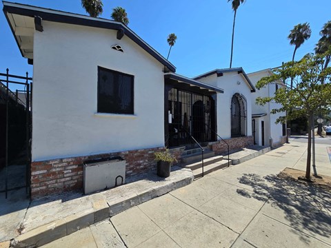 the front of a white building with a black window and a sidewalk