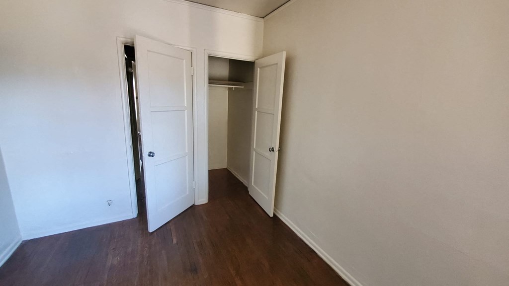 A room with a white door and a wooden floor.