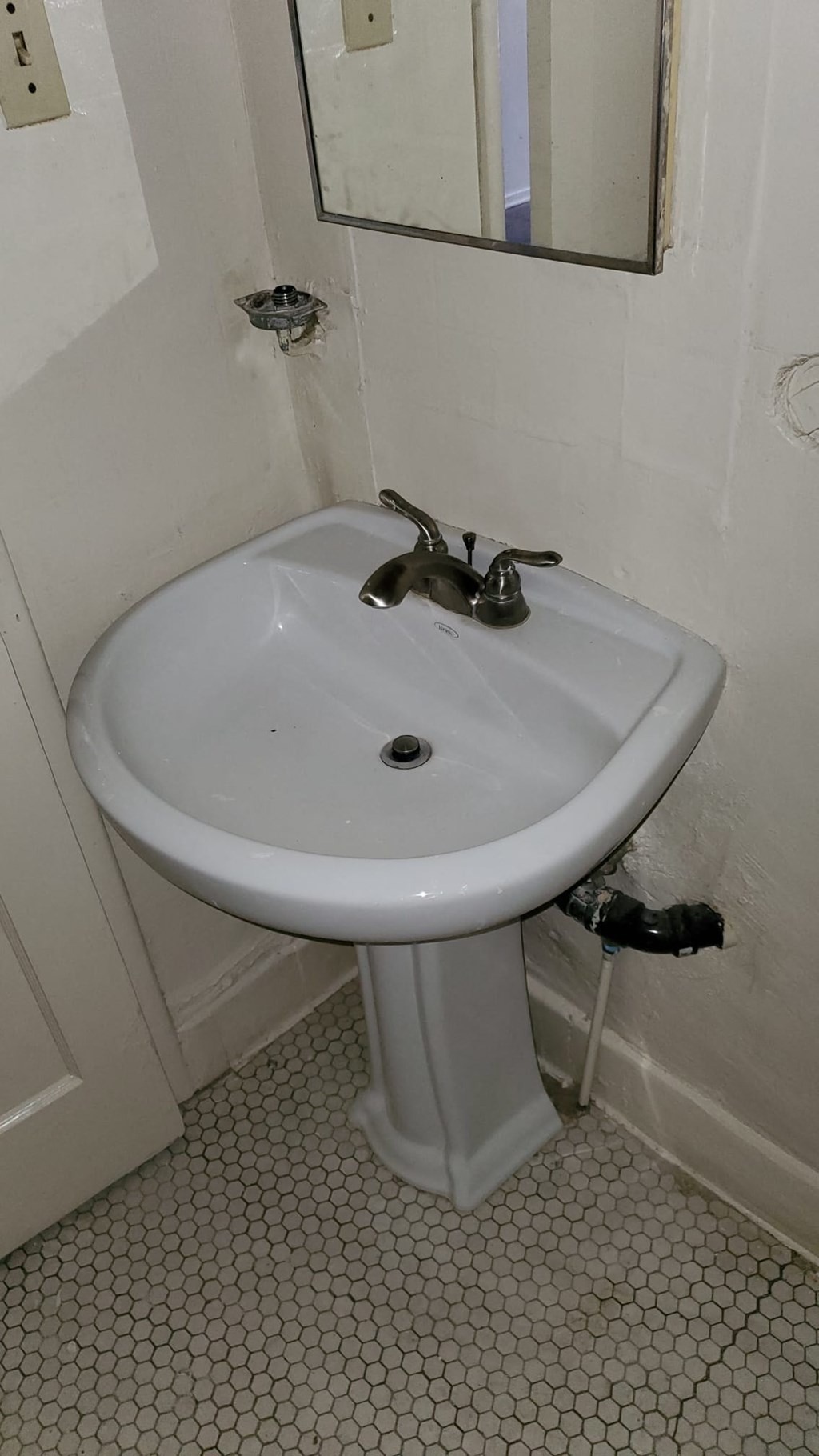 A white pedestal sink in a small bathroom.