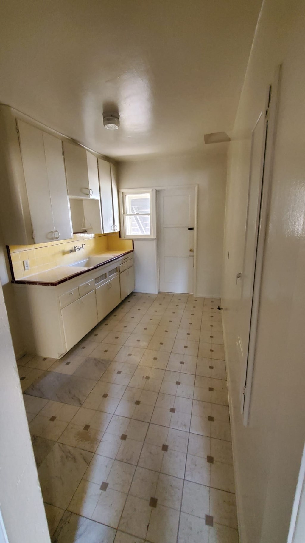 A kitchen with white cabinets and a tiled floor.