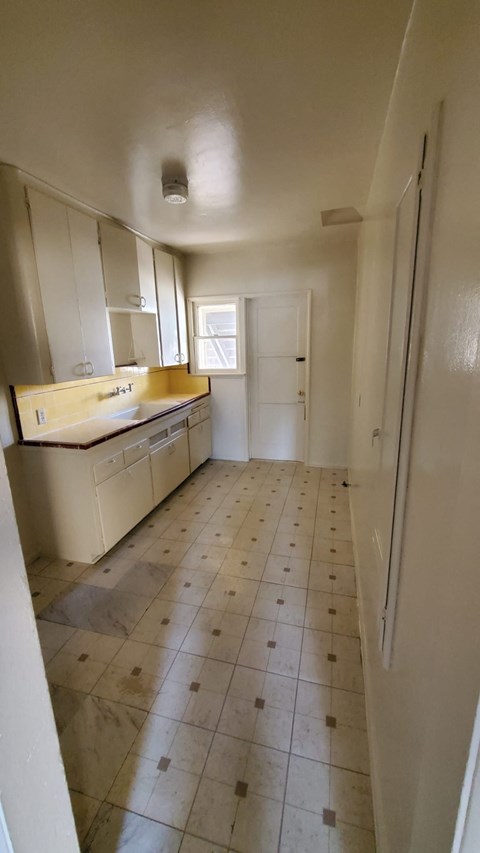 A kitchen with white cabinets and a tiled floor.