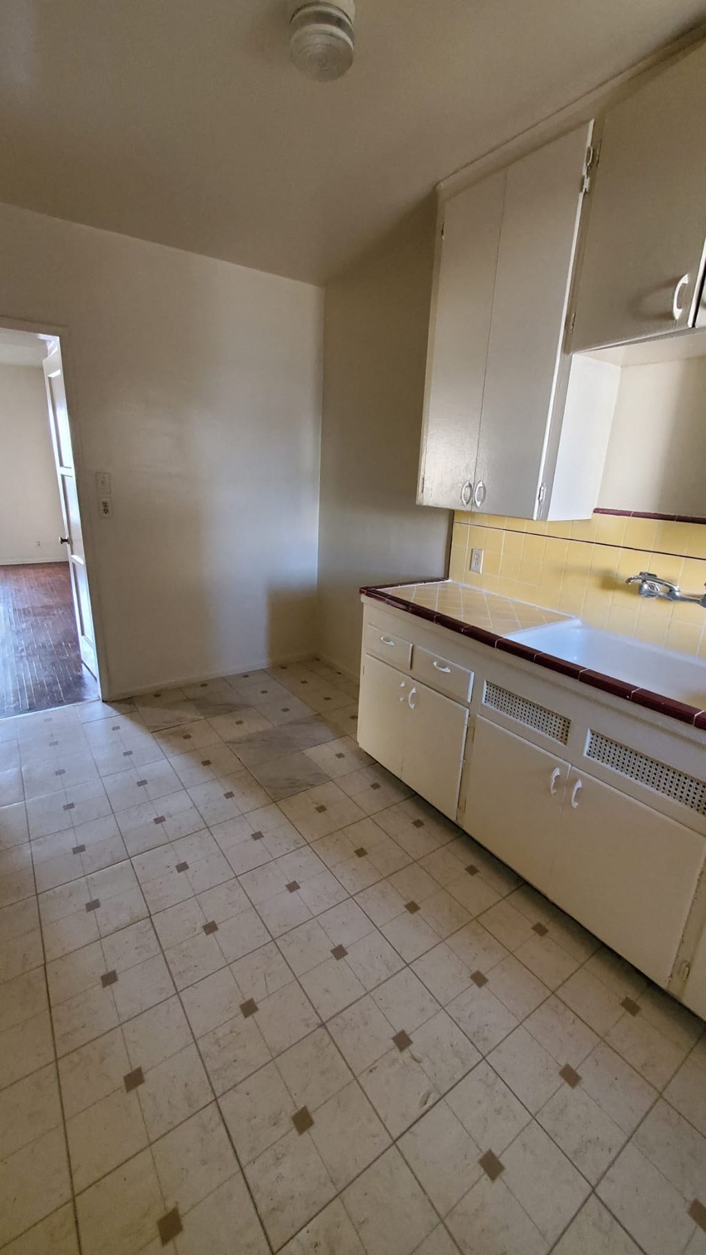 A kitchen with white cabinets and a tiled floor.