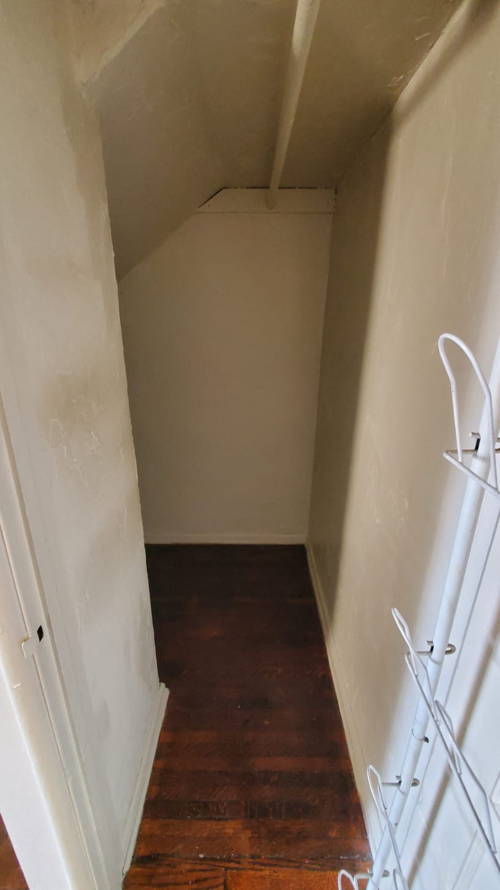 A hallway with a wooden floor and white walls.