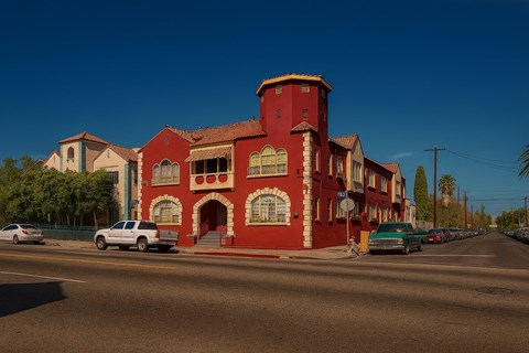 A red building with a white car parked in front of it.