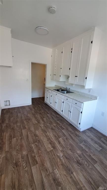 A kitchen with white cabinets and a wooden floor.