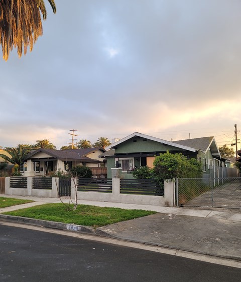 A house with a green roof and a fence in front of it.