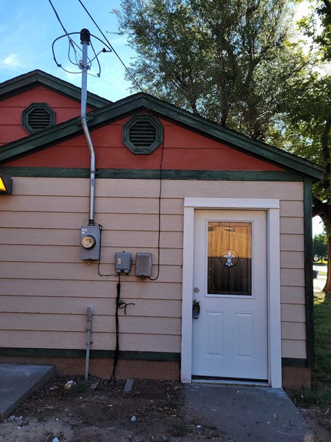 a small building with a white door and a power line next to it