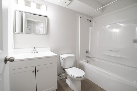 A white bathroom with a toilet, sink, and bathtub.