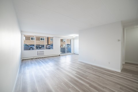 A spacious room with wooden flooring and white walls.