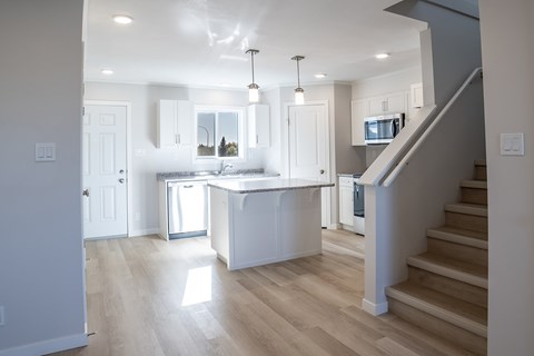 A modern kitchen with a staircase leading to the upper floor.