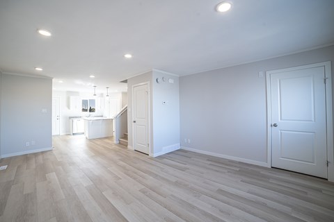 A spacious room with wooden flooring and white walls.