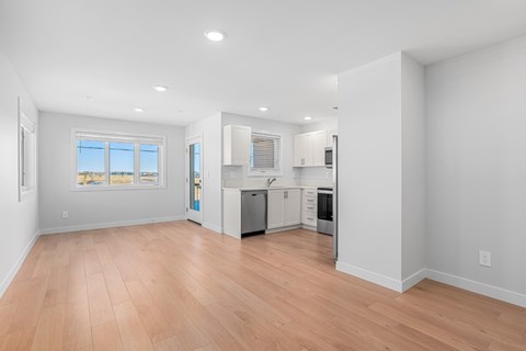 A kitchen with white cabinets and a wooden floor.