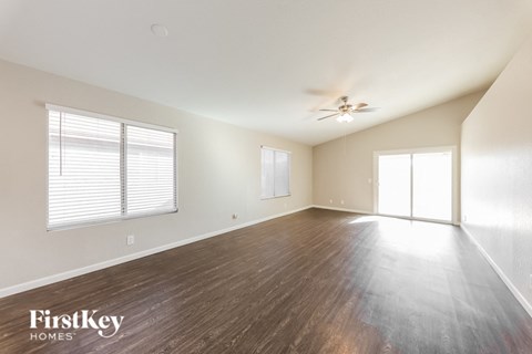 an empty living room with wood floors and a ceiling fan