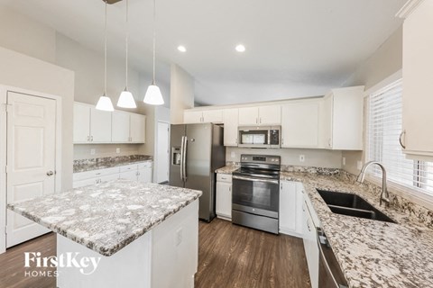 a white kitchen with marble counter tops and stainless steel appliances