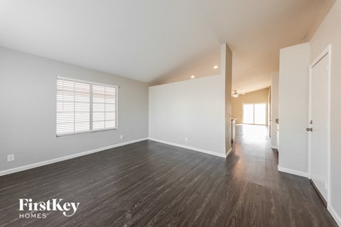 a spacious living room with hardwood floors and white walls