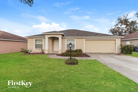 a beige house with a driveway and a lawn