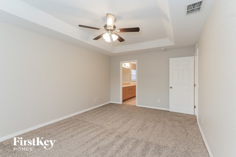 a spacious living room with a ceiling fan and a carpet