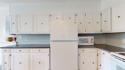 a white kitchen with white cabinets and a white refrigerator