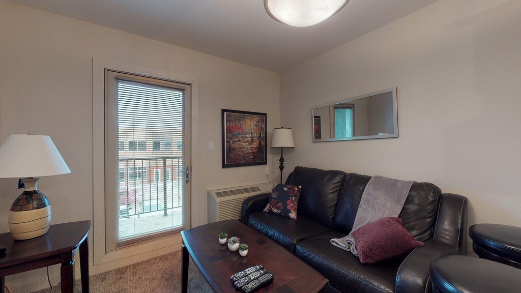 A living room with a black leather couch and a coffee table.