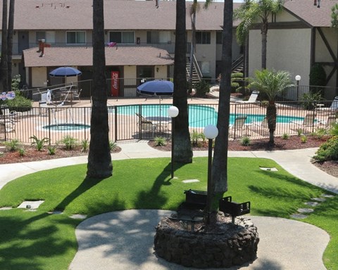 A pool surrounded by a grassy area and trees.
