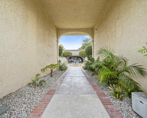 A pathway leads to a courtyard with a building in the distance.