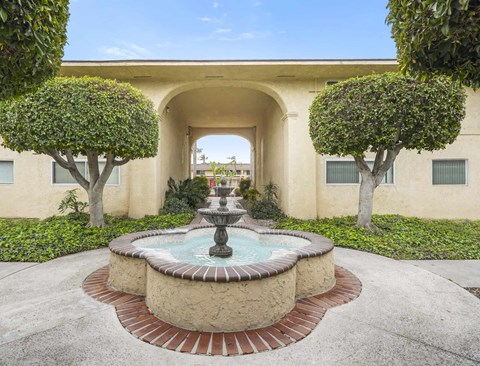 A fountain in the middle of a courtyard surrounded by trees.