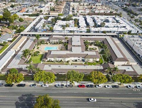 A bird's eye view of a residential area with a swimming pool and parked cars.