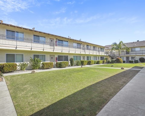 A sunny day at a well-kept apartment complex with green lawns and clear skies.