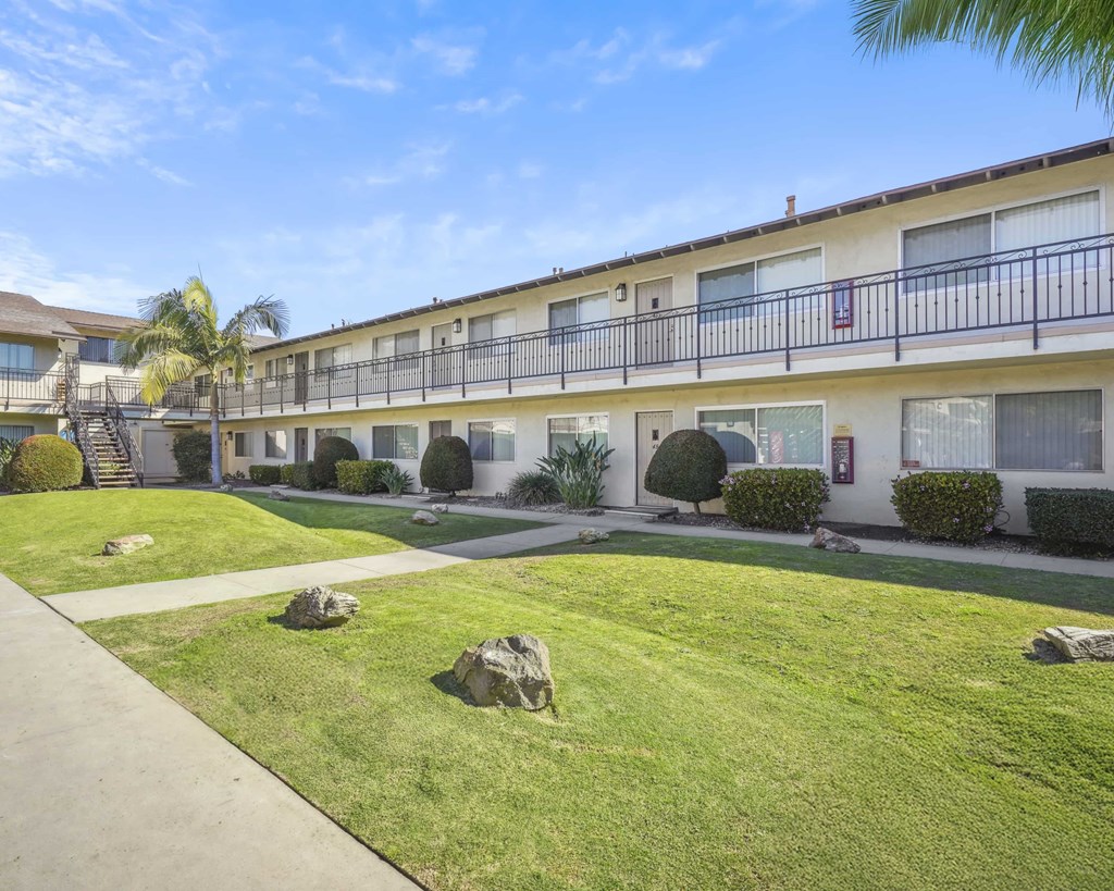 A sunny day at a well-kept apartment complex with a clear blue sky.