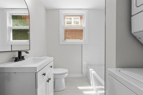 A white bathroom with a toilet, sink, and bathtub.