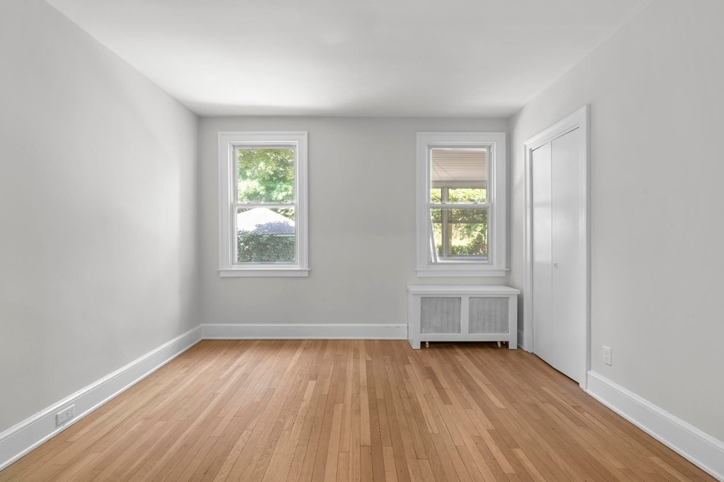 A room with wooden floors and two windows.