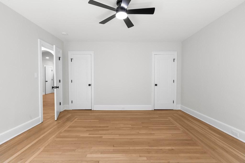 A room with a ceiling fan and wooden flooring.