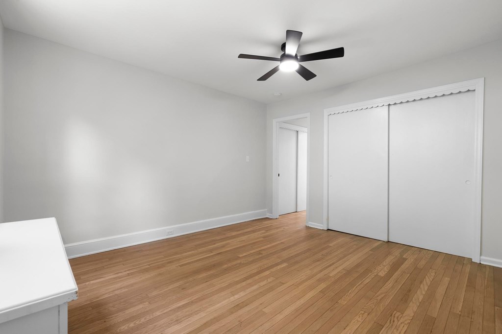 A room with a ceiling fan and wooden flooring.