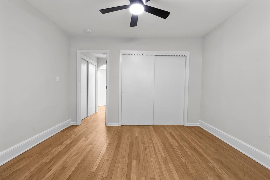 A room with a ceiling fan and wooden flooring.