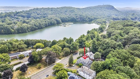 A red arrow points to a house in a lush green area.