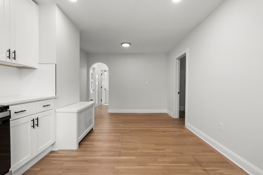 A kitchen with white cabinets and a wooden floor.