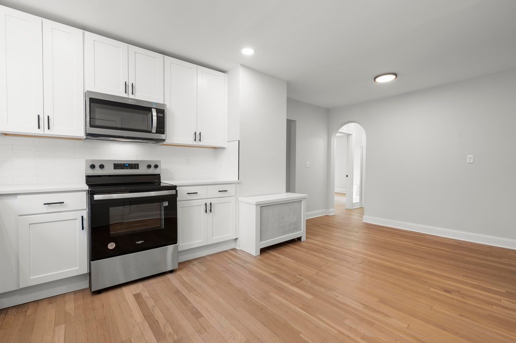 A kitchen with white cabinets and a wooden floor.