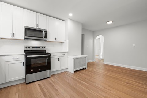 A kitchen with white cabinets and a wooden floor.