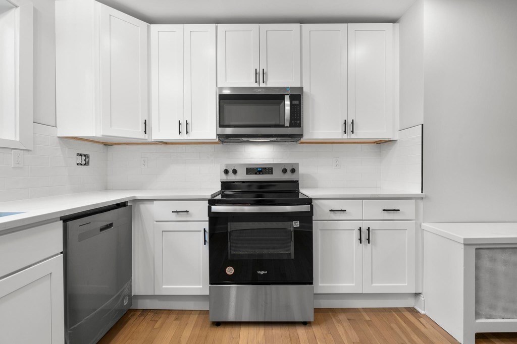 A modern kitchen with white cabinets and stainless steel appliances.
