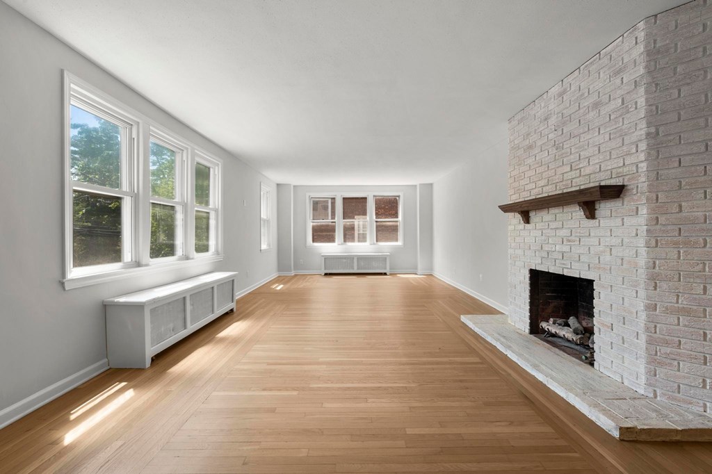 A white room with a fireplace and wooden floors.
