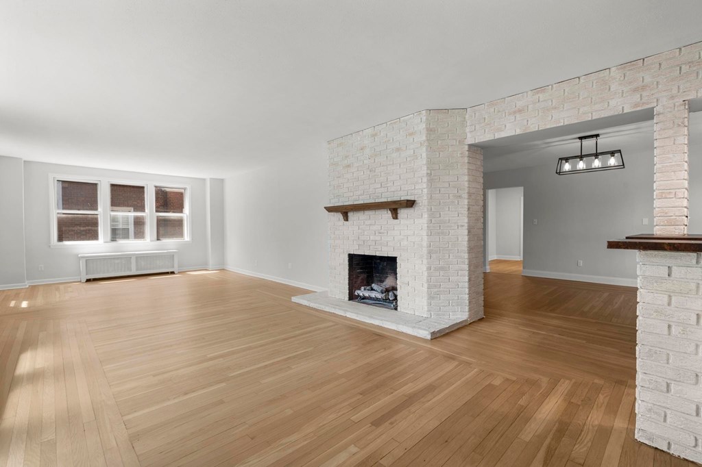A white brick fireplace in a room with wooden floors.