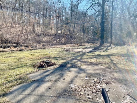 A road with a black pipe on the right side and trees in the background.