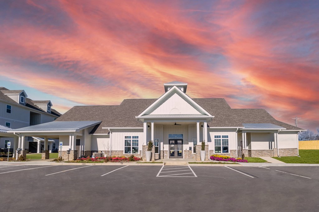 a building with a parking lot and a cloudy sky above it