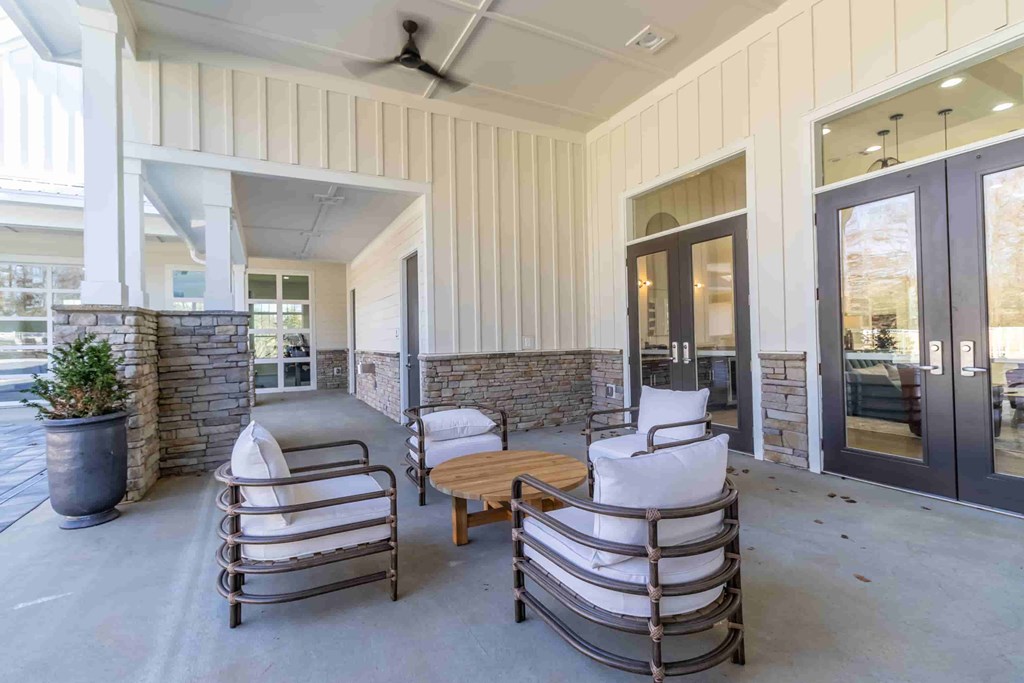 a covered porch with rocking chairs and a wooden table