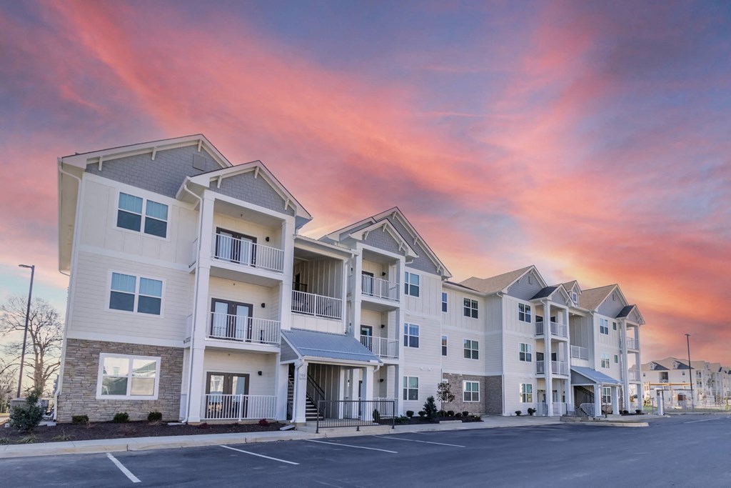 a row of apartment buildings with a sunset in the background