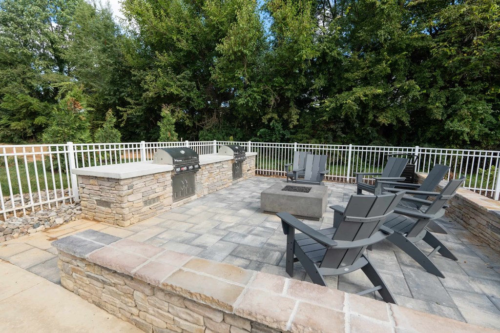 a stone patio with chairs and a fire pit