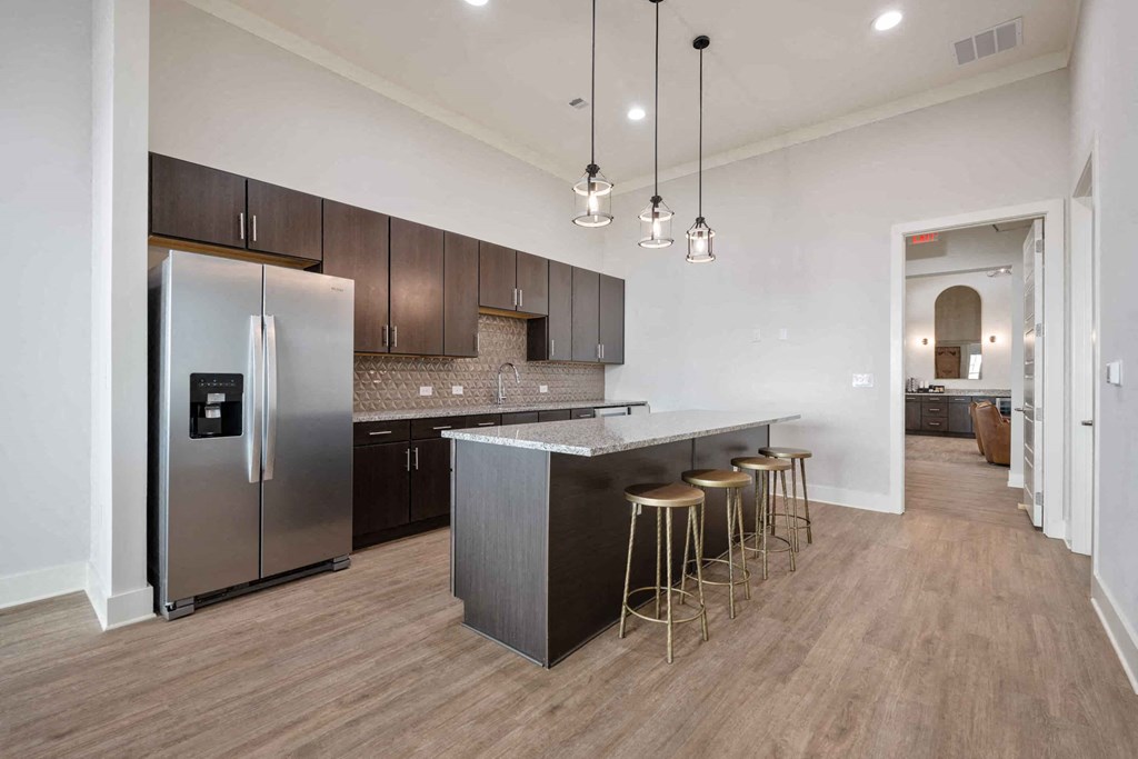 a kitchen with stainless steel appliances and a bar with three stools